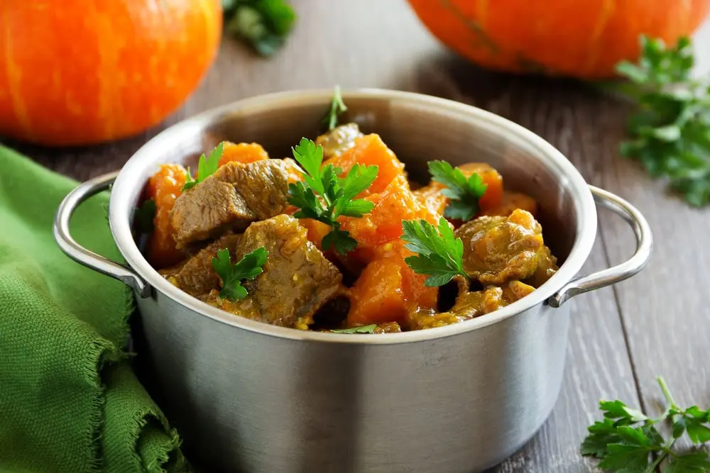 Paleo beef and pumpkin stew in a stainless steel pot with a green napkin